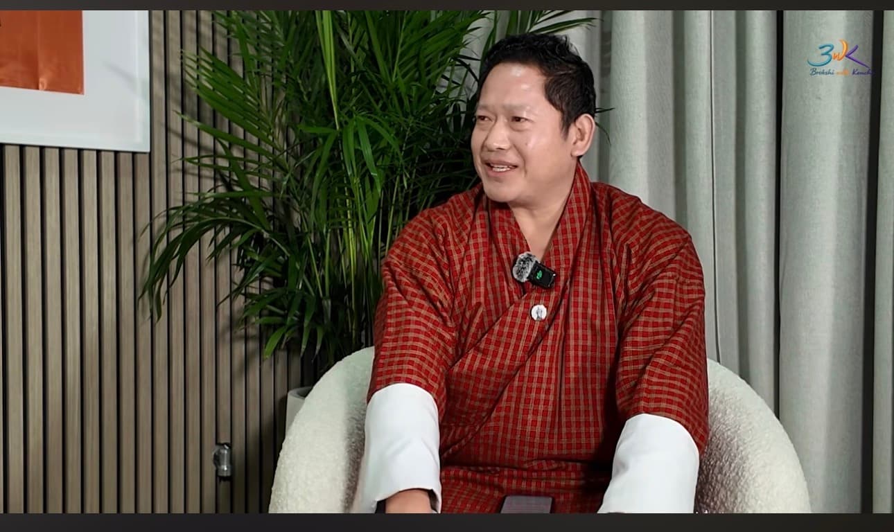 Kencho Tempa in a red gho seated in the BWK studio as the homepage hero portrait.